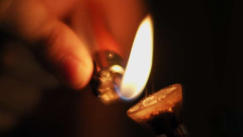 Close-up of a hand using a lighter to heat a dab nail during the dabbing process